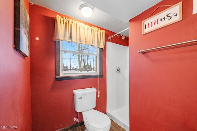 bathroom featuring a shower, hardwood / wood-style floors, and toilet