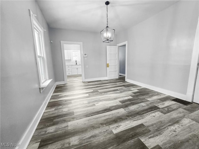 unfurnished dining area featuring dark hardwood / wood-style floors, an inviting chandelier, and sink