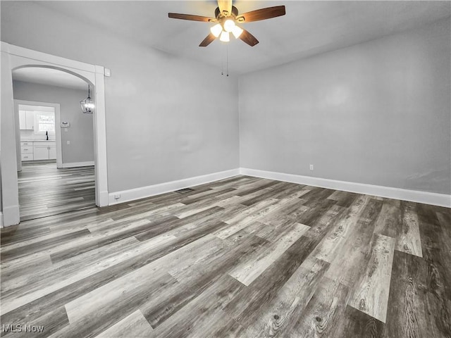 empty room featuring ceiling fan, sink, and dark wood-type flooring