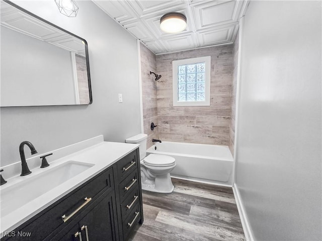 full bathroom featuring vanity, tiled shower / bath combo, hardwood / wood-style flooring, and toilet