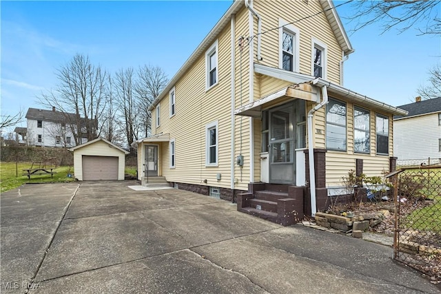 view of property exterior with entry steps, concrete driveway, a detached garage, and an outbuilding