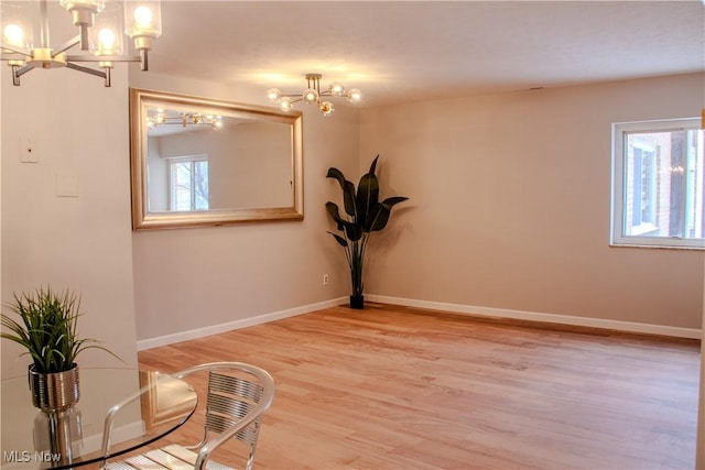 empty room with hardwood / wood-style floors and an inviting chandelier