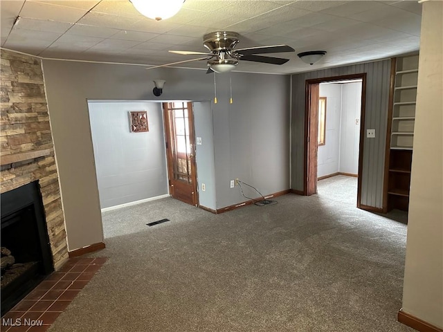 unfurnished living room featuring ceiling fan, a fireplace, and dark colored carpet