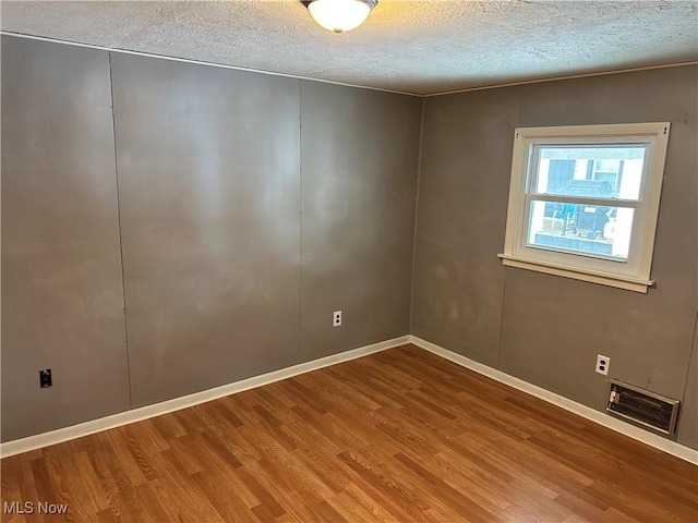 empty room with hardwood / wood-style floors and a textured ceiling