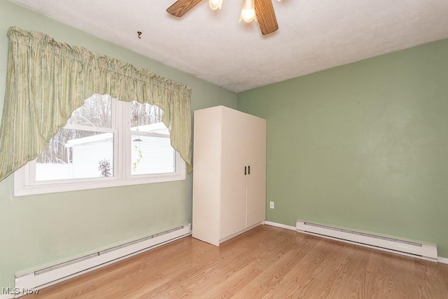 empty room with light hardwood / wood-style flooring, a wealth of natural light, and a baseboard radiator