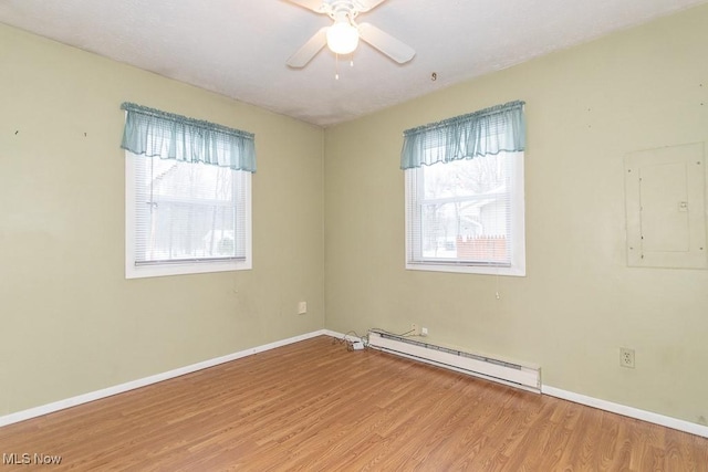 empty room with electric panel, a baseboard radiator, ceiling fan, and light hardwood / wood-style flooring