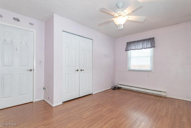 unfurnished bedroom with ceiling fan, a closet, a baseboard radiator, and light wood-type flooring