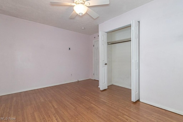 unfurnished bedroom with hardwood / wood-style floors, a textured ceiling, a closet, and ceiling fan