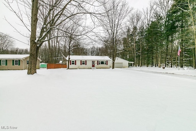 snowy yard featuring an outbuilding and a garage