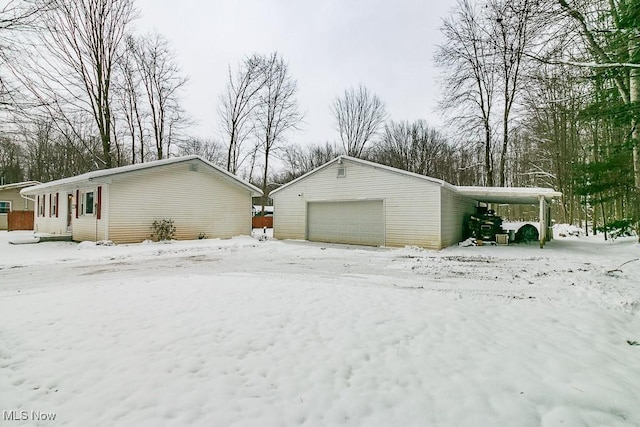 snow covered garage featuring a carport