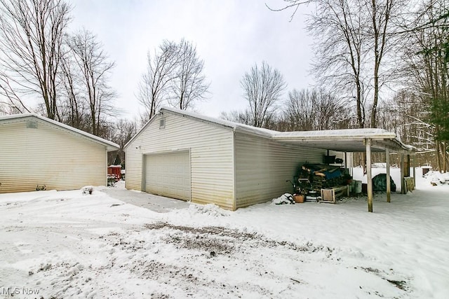 snow covered garage with a carport