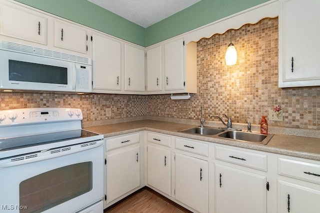 kitchen with white appliances, backsplash, white cabinetry, and sink