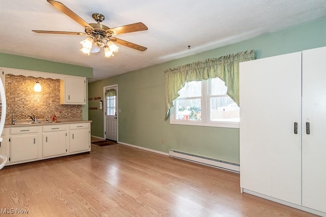 kitchen featuring white cabinets, a healthy amount of sunlight, tasteful backsplash, and a baseboard heating unit