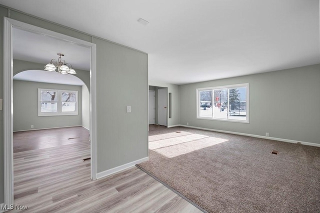 spare room with light hardwood / wood-style floors and an inviting chandelier