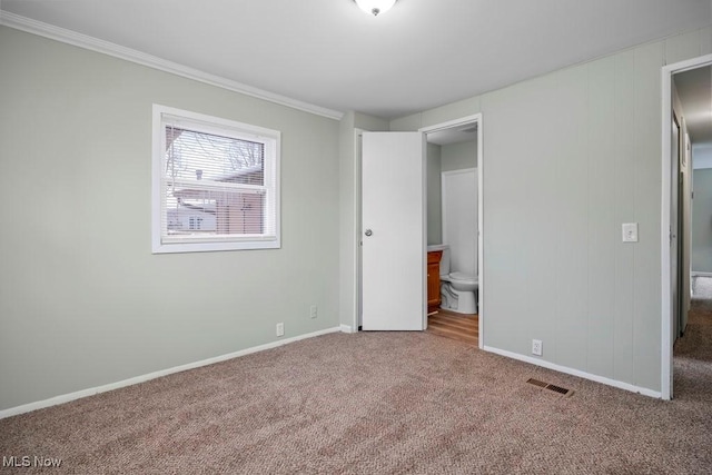 unfurnished bedroom with carpet, crown molding, and connected bathroom