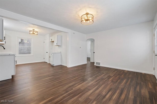 unfurnished living room with a chandelier, sink, and dark wood-type flooring