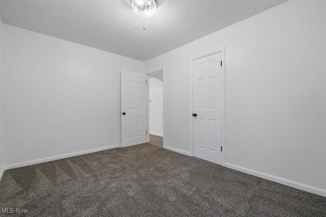 unfurnished bedroom with dark colored carpet, a textured ceiling, and a closet