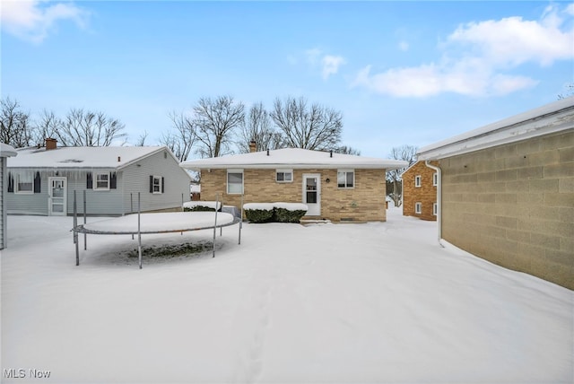 snow covered house featuring a trampoline