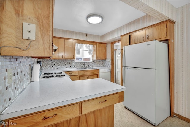 kitchen with backsplash, kitchen peninsula, white appliances, and sink