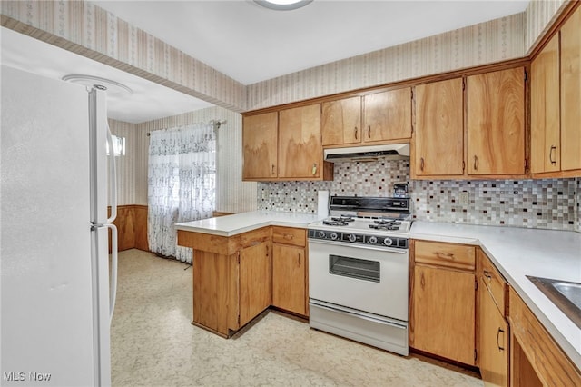 kitchen with kitchen peninsula, white appliances, and tasteful backsplash