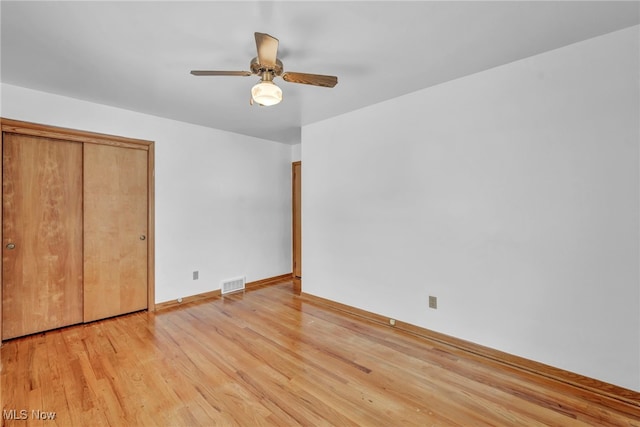 unfurnished bedroom featuring ceiling fan, light wood-type flooring, and a closet