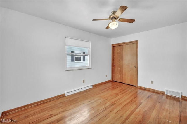 spare room with ceiling fan, light wood-type flooring, and a baseboard radiator