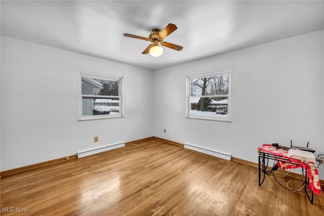 empty room featuring baseboard heating, ceiling fan, and light hardwood / wood-style floors