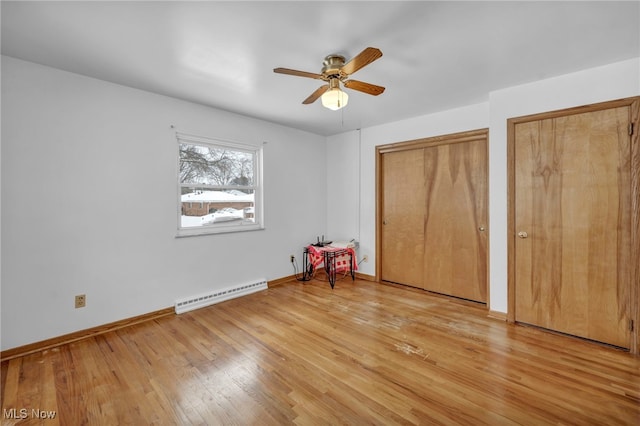 unfurnished bedroom with multiple closets, ceiling fan, a baseboard radiator, and light wood-type flooring