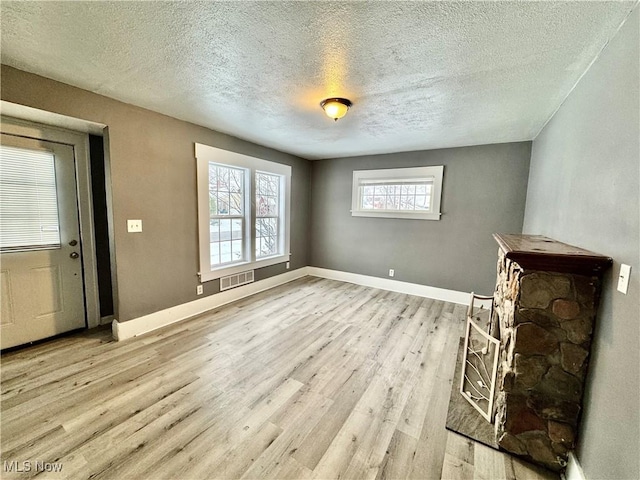 unfurnished living room with a textured ceiling and light wood-type flooring