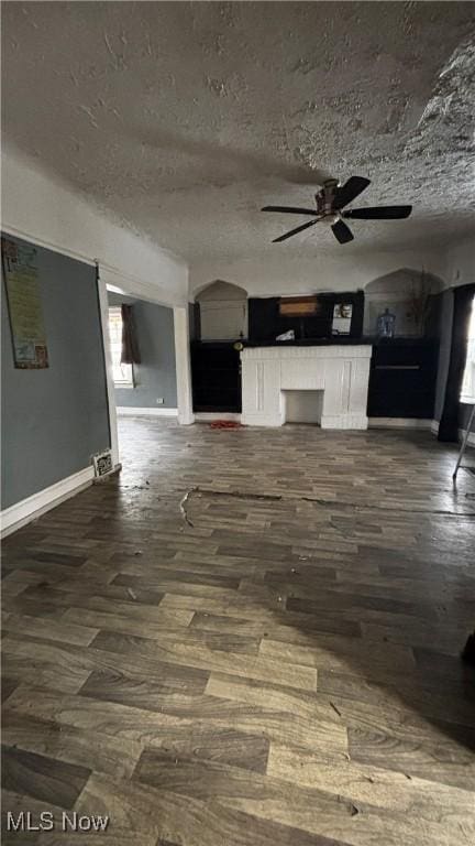 unfurnished living room featuring a textured ceiling, dark hardwood / wood-style flooring, and ceiling fan