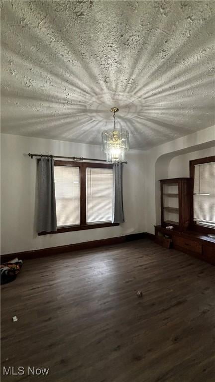 unfurnished living room with dark hardwood / wood-style flooring and a textured ceiling