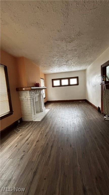 unfurnished living room with dark hardwood / wood-style floors and a textured ceiling