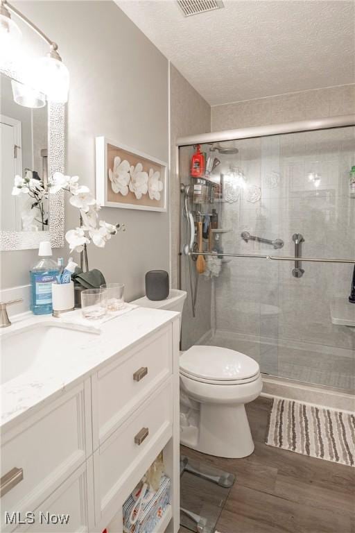 bathroom featuring vanity, a textured ceiling, hardwood / wood-style flooring, and an enclosed shower