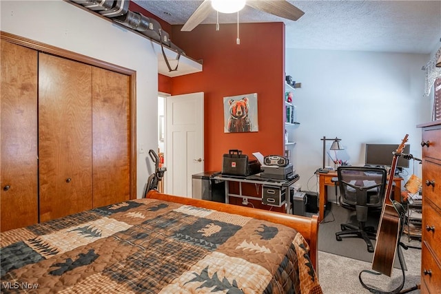 carpeted bedroom with ceiling fan, a textured ceiling, and a closet