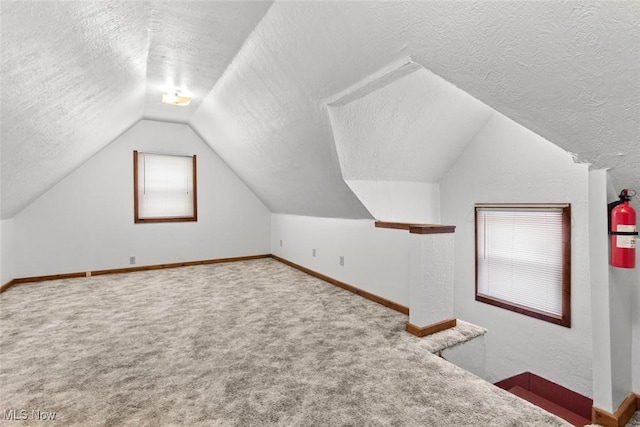 bonus room with a textured ceiling, light carpet, and vaulted ceiling