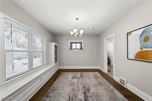 dining area with a wealth of natural light, dark hardwood / wood-style flooring, and an inviting chandelier