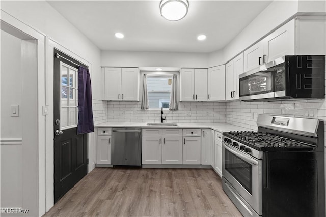 kitchen with appliances with stainless steel finishes, tasteful backsplash, white cabinetry, and sink