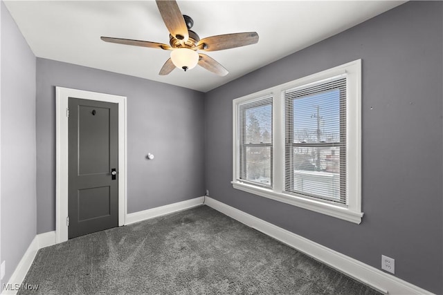 unfurnished room with ceiling fan and dark carpet