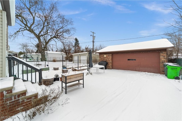 snow covered deck featuring an outdoor structure and a garage