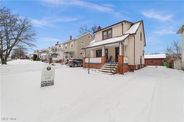 snow covered property with covered porch