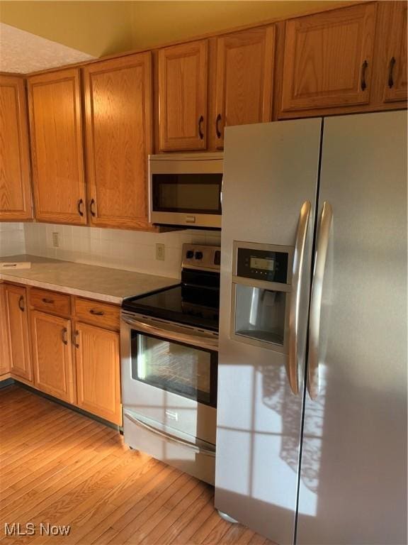 kitchen with light hardwood / wood-style flooring and appliances with stainless steel finishes