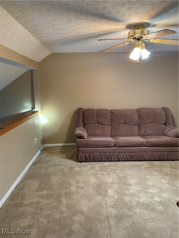 unfurnished living room featuring a textured ceiling, ceiling fan, carpet, and lofted ceiling