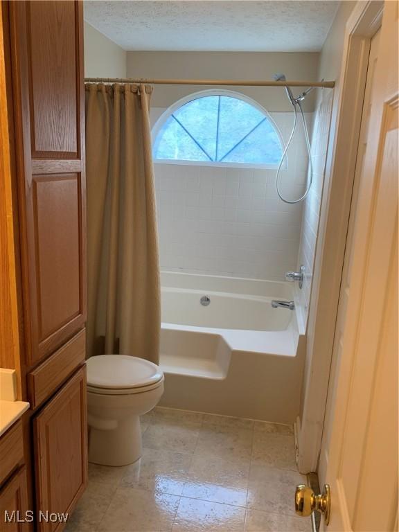 full bathroom featuring shower / bath combination with curtain, toilet, a textured ceiling, and vanity