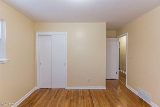 unfurnished bedroom featuring a closet and hardwood / wood-style floors