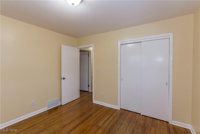 unfurnished bedroom with dark wood-type flooring and a closet