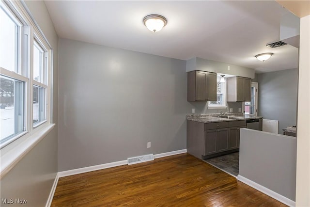 kitchen featuring gray cabinetry, dishwasher, and dark hardwood / wood-style flooring