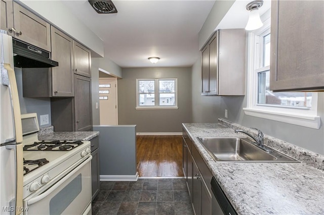 kitchen with white range with gas cooktop, sink, and range hood