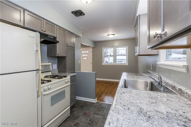 kitchen featuring a healthy amount of sunlight, dark brown cabinetry, white appliances, and sink