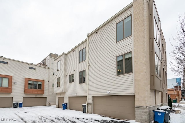snow covered house featuring a garage