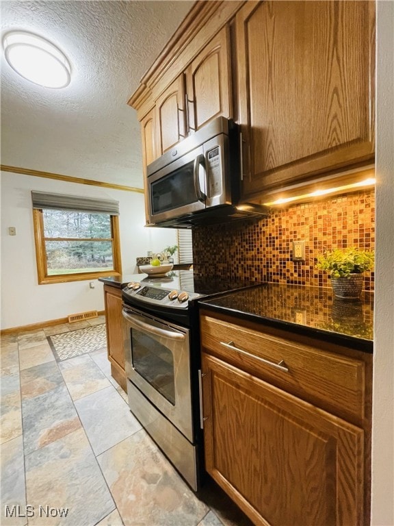 kitchen with backsplash, a textured ceiling, and appliances with stainless steel finishes